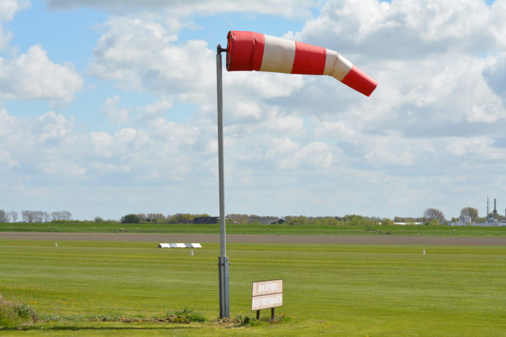 A red and white striped windsock at an airport runway